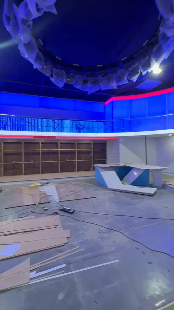 News studio set build in progress with blue and red LED lighting