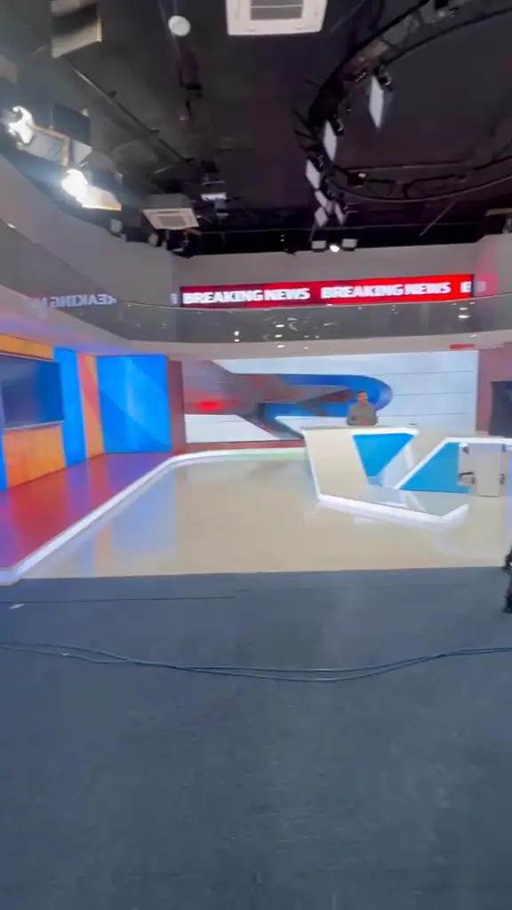 Completed RTV news studio set with anchor desk, LED walls and lighting grid